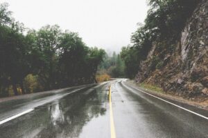 A wet two lane road on an overcast day